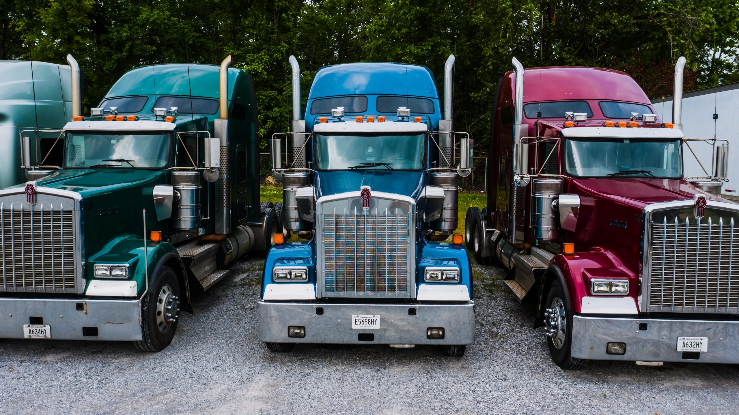Blue, green and red semi trucks parked side by side