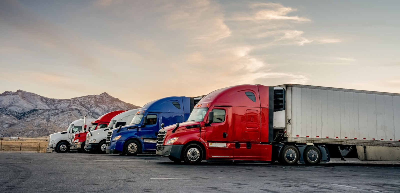 Red, blue and white sleeper trucks with trailers parked together